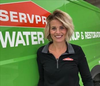 Female employee, Stacey, standing by green SERVPRO van