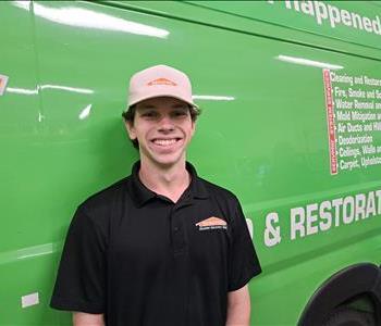 Male employee, Clayton, standing in front of green SERVPRO van