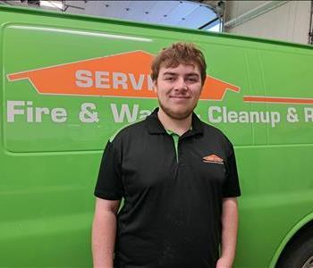 Male employee, Casey, standing in front of SERVPRO van