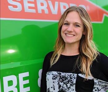 Female employee, Molly, standing in front of green SERVPRO van