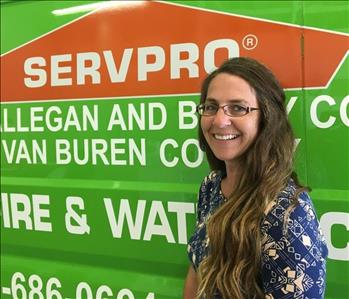 Female owner with glasses standing in front of SERVPRO van