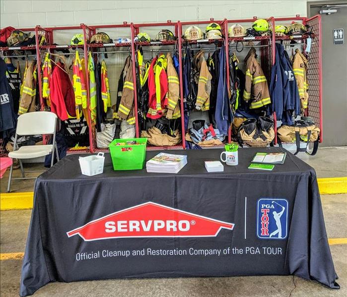 SERVPRO table set with goodies with fire firefighter uniforms behind