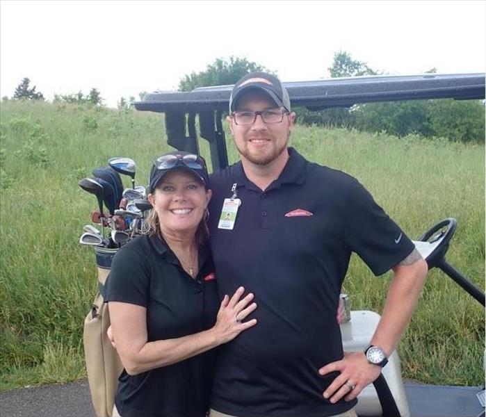 Female and Male employees standing in front of golf cart